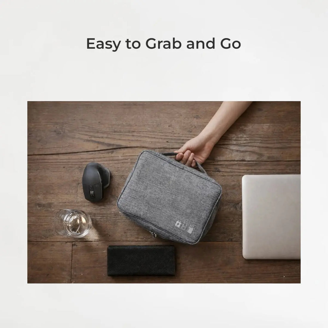 Gray carrying case held by a hand on a wooden surface with office items.