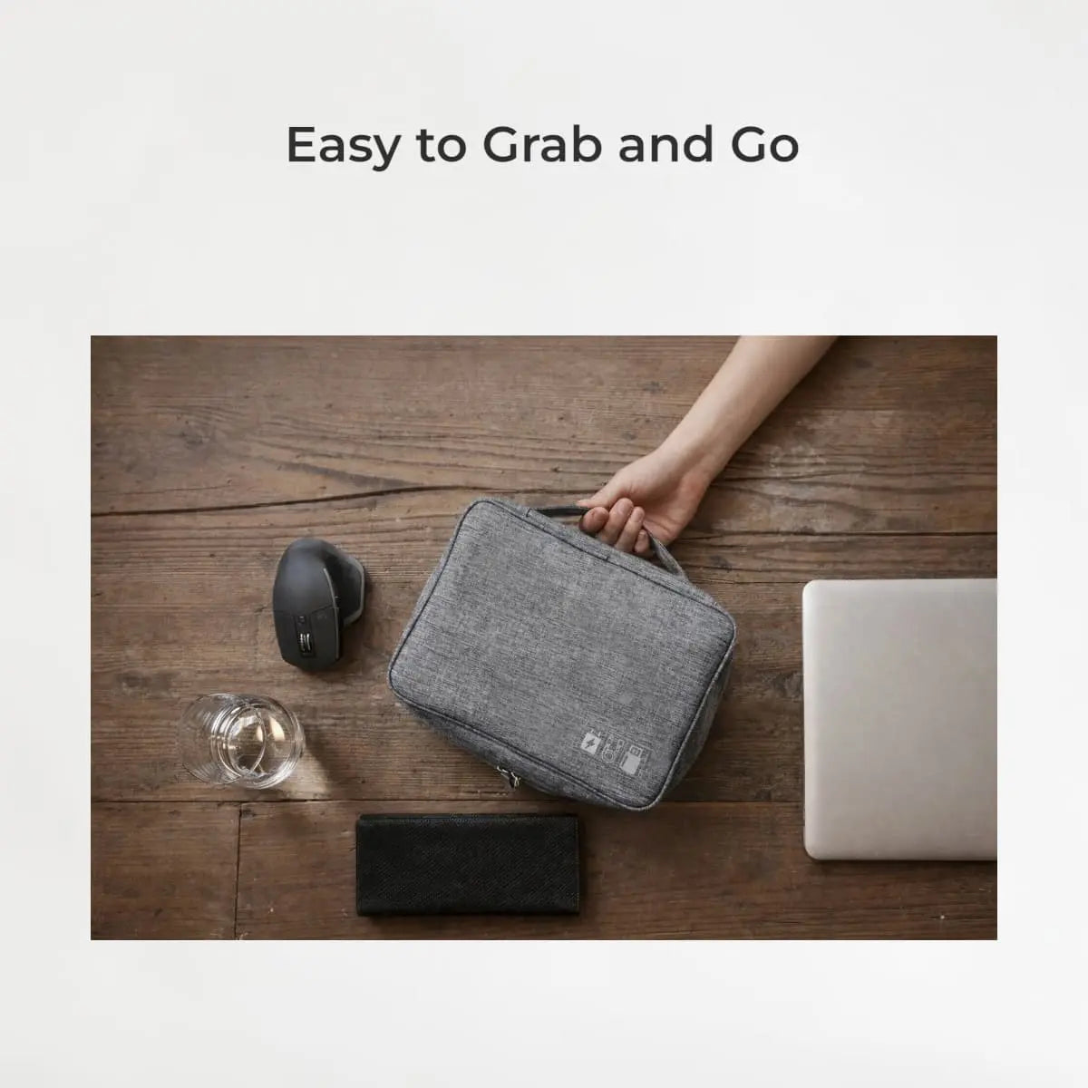 Gray carrying case held by a hand on a wooden surface with office items.